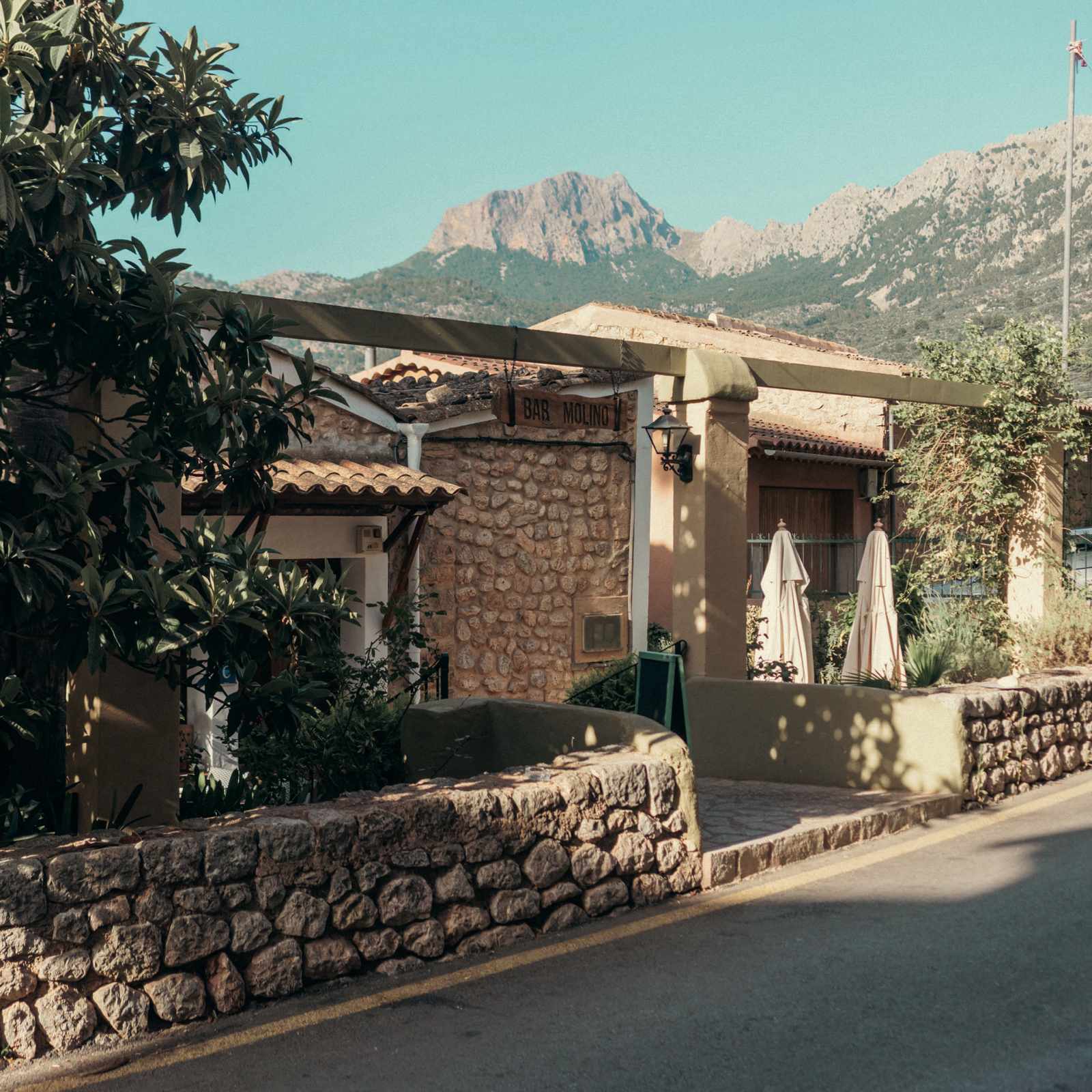 Exterior del Bar Molino en Sóller, casa de piedra ante las montañas de la Tramuntana